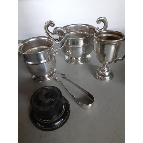 307 - Four items of silver to include a twin handled pedestal bowl, a trophy, a cream jug and sugar nips, ... 