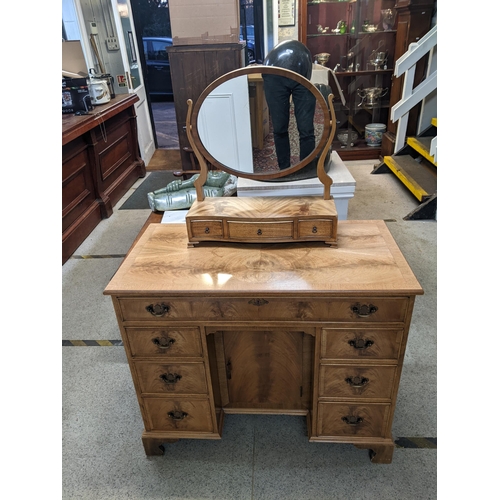 313 - A 20th century walnut desk with seven drawers and a door on bracket feet, and a matching swing mirro... 