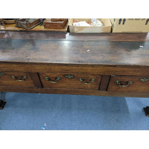 408 - A Georgian oak dresser base having three drawers with brass swan neck handles and on squared cut-dow... 