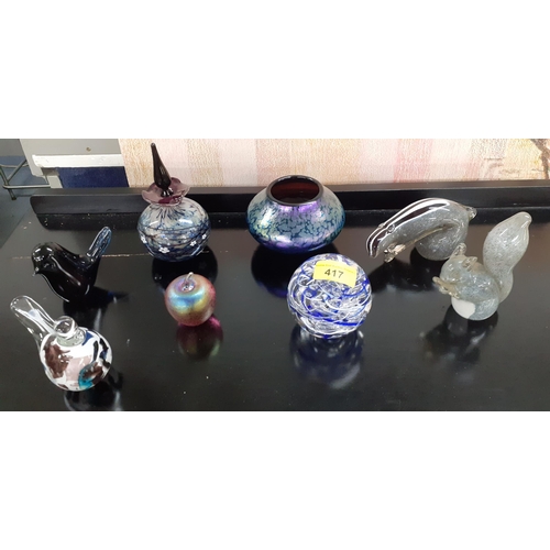 417 - A small quantity of glass paperweights to include Langham together with a purple iridescent bowl in ... 