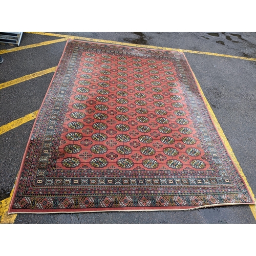 440 - A Middle Eastern machine woven red ground rug having repeating motifs and multiguard borders, 347cm ... 