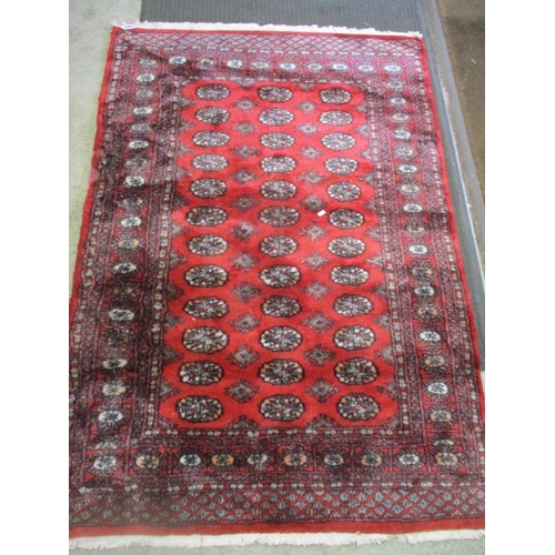 104 - A Pakistan handwoven red ground rug decorated with elephant gulls and geometric devices, multiguard ... 