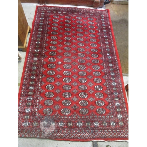 104 - A Pakistan handwoven red ground rug decorated with elephant gulls and geometric devices, multiguard ... 