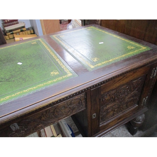 105 - A mid to late 20th century oak kneehole writing desk, the top with three panels of green leather scr... 