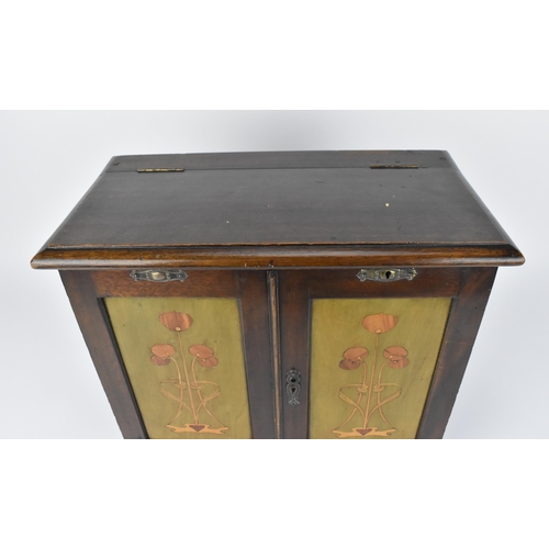 44 - An Art Nouveau mahogany smokers cabinet, the front hinged doors with marquetry panels of stylised tu... 