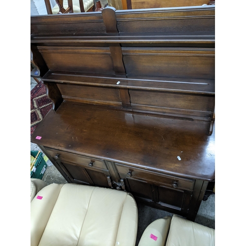 255 - An Ercol style dresser, the top with two plate shelves over a base with two drawers over twin panell... 