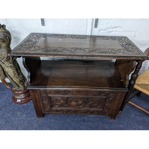 18 - An early 20th century oak carved monk's bench having floral and scroll carving and a hinged seat 93c... 
