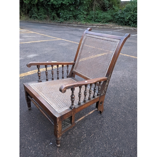 257 - A late 19th/early 20th century cane seated armchair having a carved and pierced frame with turned sp... 