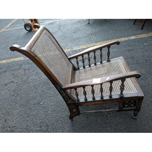 257 - A late 19th/early 20th century cane seated armchair having a carved and pierced frame with turned sp... 