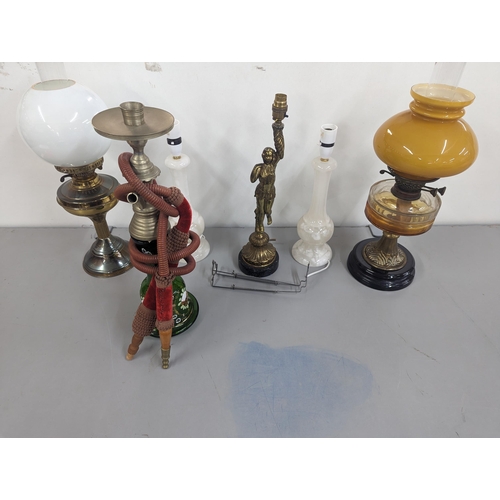 471 - A group of lamps to include two brass oil lamps with glass shades, a brass lamp in the form of a fig... 