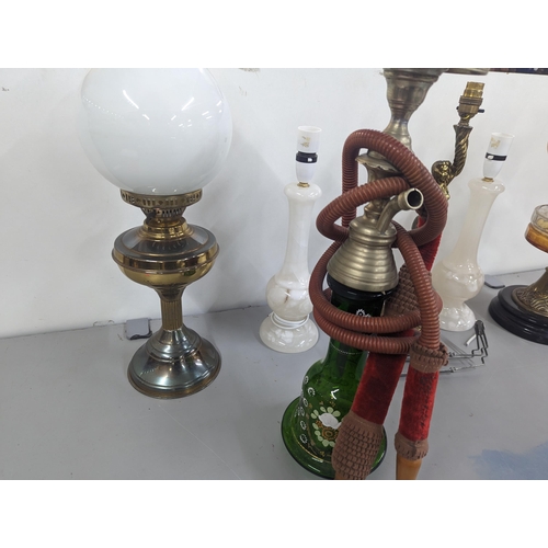 471 - A group of lamps to include two brass oil lamps with glass shades, a brass lamp in the form of a fig... 