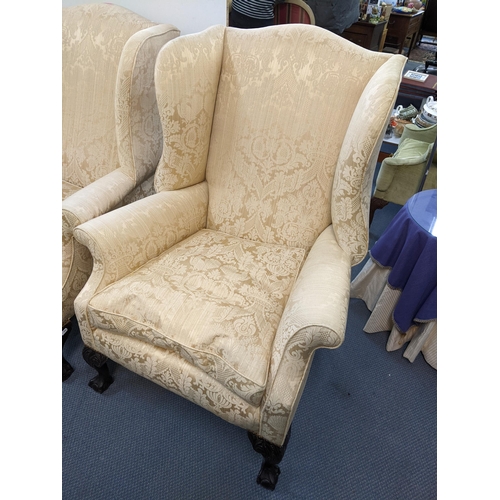 6 - A pair of early 20th century beige upholstered wing back armchairs standing on ball and claw feet
Lo... 