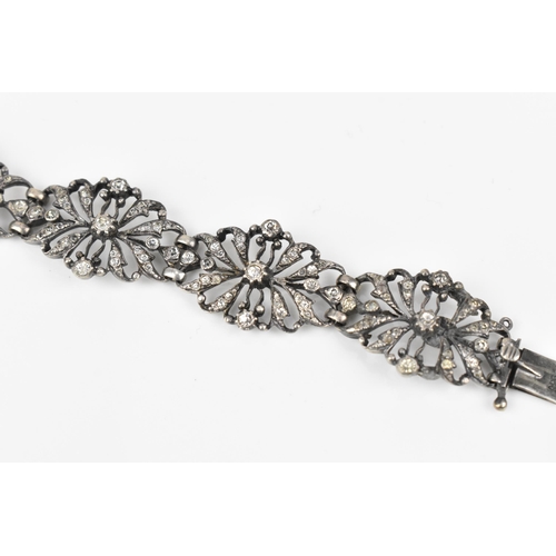 432 - An early 20th century Edwardian silver and paste bracelet, the floral openwork inset with paste thro... 