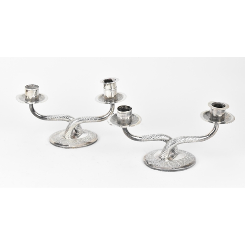 444 - A pair of Malaysian, Kelantan white metal twin-candelabra, modelled as two scaled arms with plain no... 