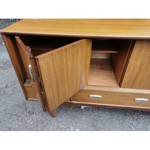 300 - A mid-century G-plan teak 'fresco' sideboard, with two folding doors each enclosing a shelf, over th... 