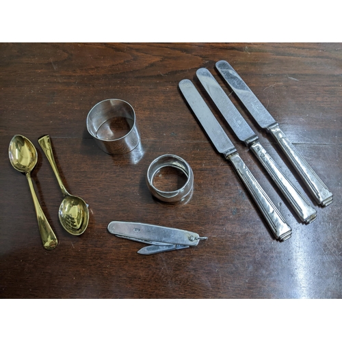 158 - A small selection of silver items to include a silver clad penknife, two napkin rings, two silver gi... 