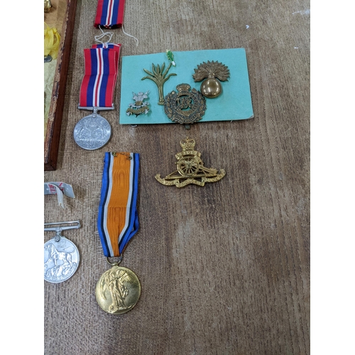 58 - A group of WWI and WWII campaign medals, cap badges, buttons, buckles and other items to include a V... 