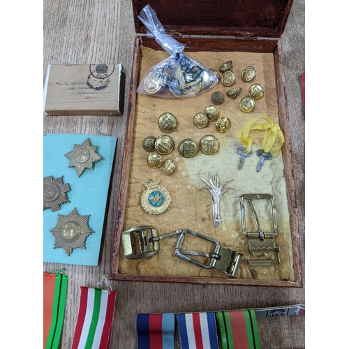 58 - A group of WWI and WWII campaign medals, cap badges, buttons, buckles and other items to include a V... 