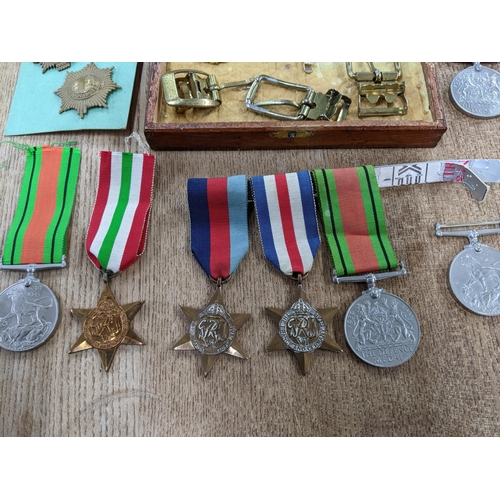 58 - A group of WWI and WWII campaign medals, cap badges, buttons, buckles and other items to include a V... 