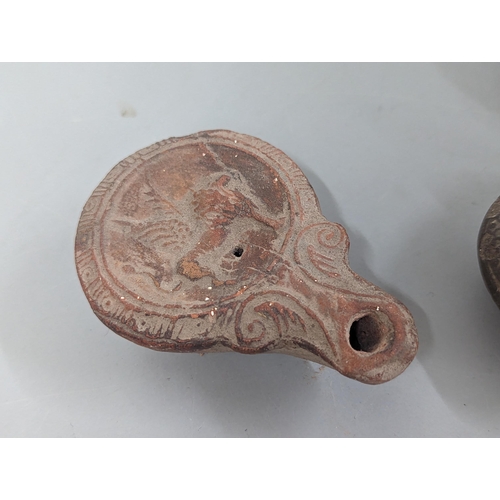 66 - A group of three possibly Roman/Classical terracotta oil lamps, to include one having circular conca... 