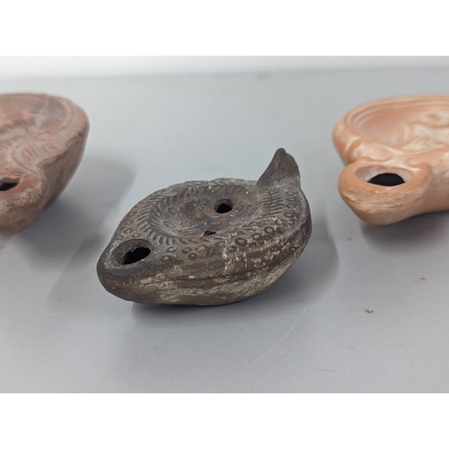 66 - A group of three possibly Roman/Classical terracotta oil lamps, to include one having circular conca... 