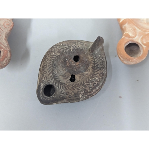 66 - A group of three possibly Roman/Classical terracotta oil lamps, to include one having circular conca... 