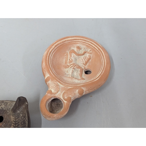 66 - A group of three possibly Roman/Classical terracotta oil lamps, to include one having circular conca... 