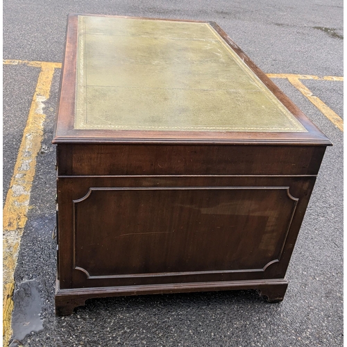 10 - A mid 20th century mahogany twin pedestal writing desk having a green leather topped scriber and nin... 