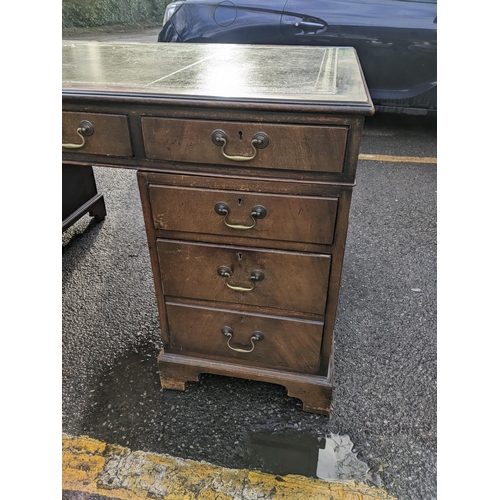 10 - A mid 20th century mahogany twin pedestal writing desk having a green leather topped scriber and nin... 