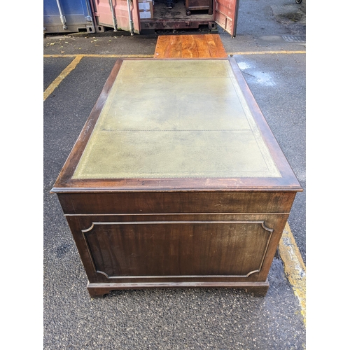 10 - A mid 20th century mahogany twin pedestal writing desk having a green leather topped scriber and nin... 