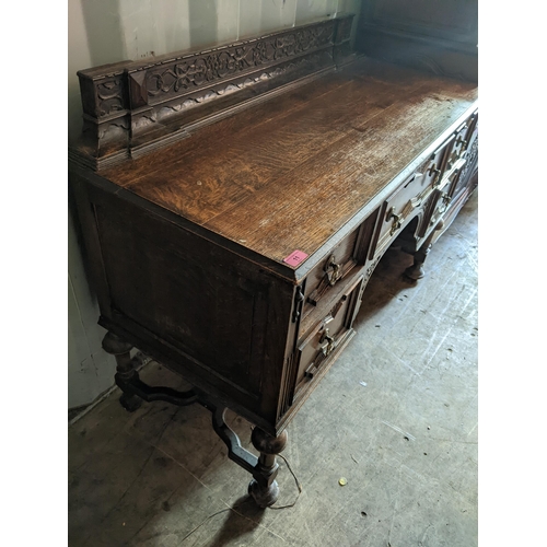 11 - An early 20th century oak desk having a raised carved back, five drawers and on turned feet, 79cm h ... 