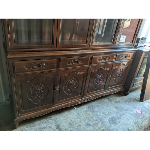 77 - A mid/late 20th century Chinese large display cabinet having four bevelled glass doors above four dr... 