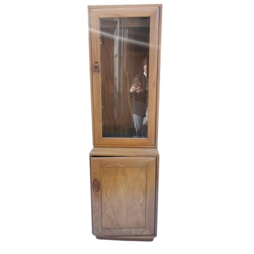 394 - A light elm Ercol glazed tall cabinet, with single glazed door above a cupboard enclosing a single s... 