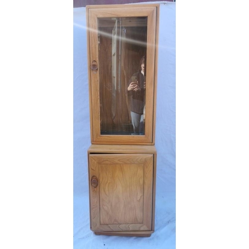 394 - A light elm Ercol glazed tall cabinet, with single glazed door above a cupboard enclosing a single s... 