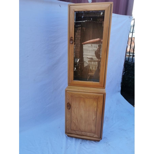 394 - A light elm Ercol glazed tall cabinet, with single glazed door above a cupboard enclosing a single s... 