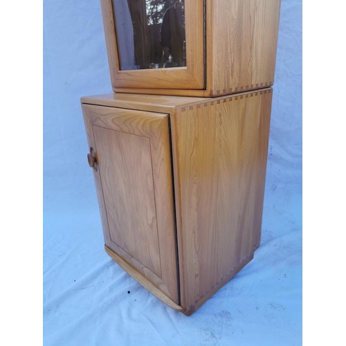 394 - A light elm Ercol glazed tall cabinet, with single glazed door above a cupboard enclosing a single s... 