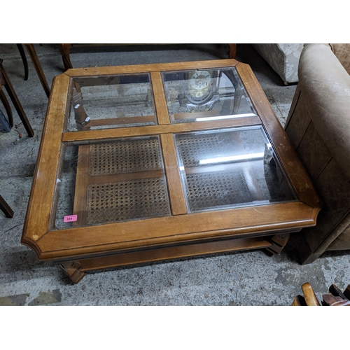 384 - A mahogany coffee table of square form with canted corner, quartered top with bevelled glass inset p... 