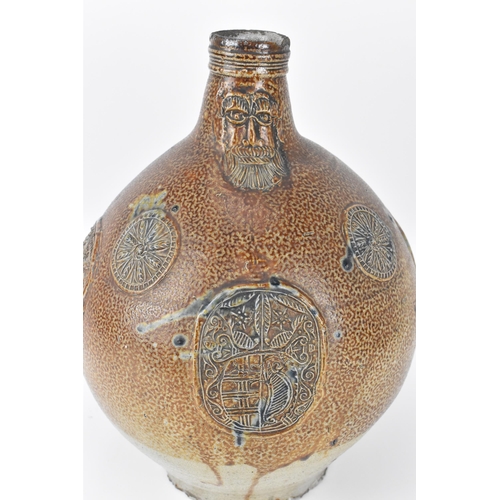 208 - A large German stoneware armorial Bellarmine, salt glazed, the mask with elongated beard above the o... 