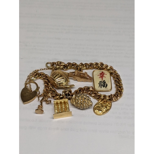 27 - A 9ct gold charm bracelet with charms, to include an 18ct gold charm, a 9ct charm in the form of a t... 