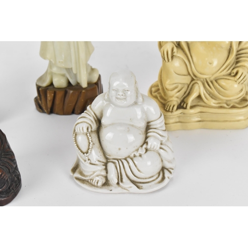 66 - A group of Oriental laughing Buddhas, comprising a dehua model, a carved wooden model and a resin on... 