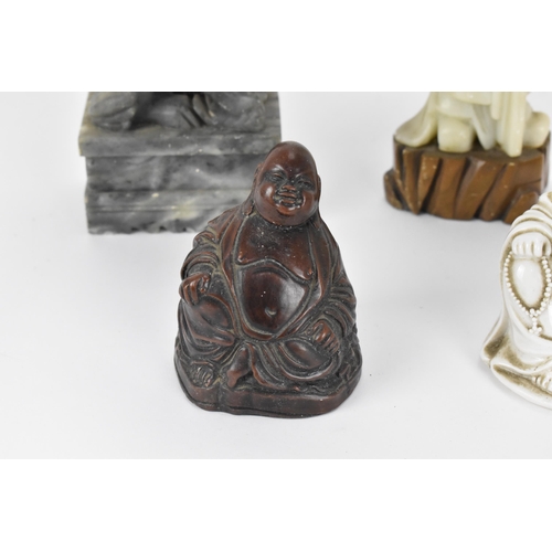 66 - A group of Oriental laughing Buddhas, comprising a dehua model, a carved wooden model and a resin on... 