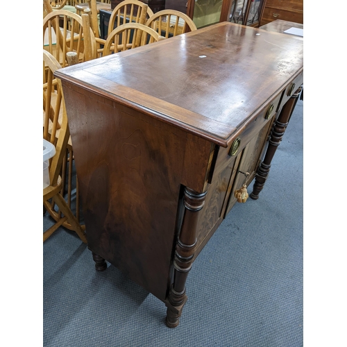 179 - A Regency Chiffonier with two short drawers above fielded, panelled cupboards, flanked by turned col... 