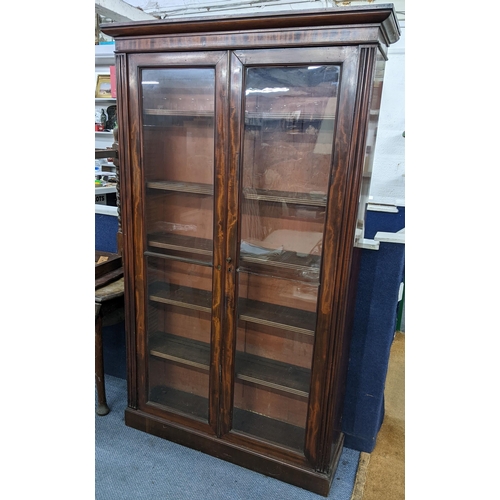 9 - An early 19th century mahogany two door glazed bookcase having a moulded cornice, loose shelves and ... 