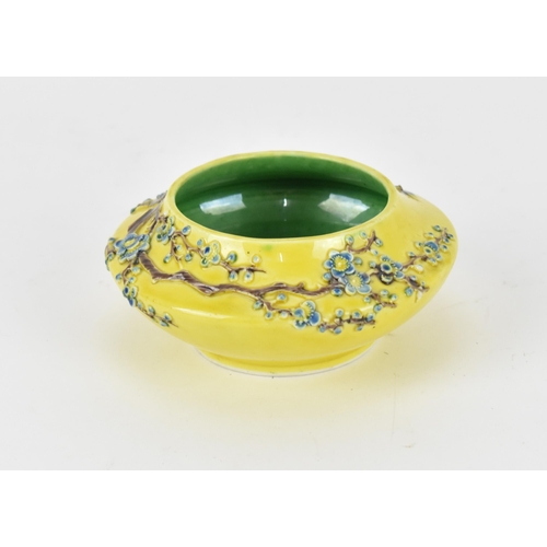 122A - A Chinese yellow ground porcelain bowl, possibly Fahua, with raised prunus branches with blue blooms... 