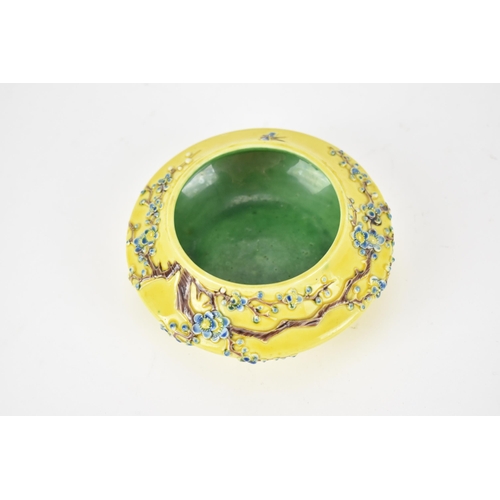 122A - A Chinese yellow ground porcelain bowl, possibly Fahua, with raised prunus branches with blue blooms... 