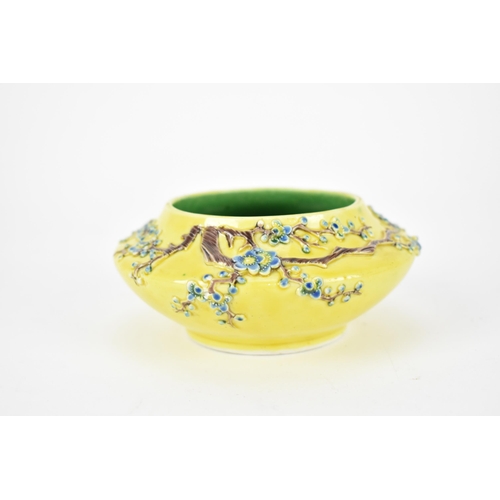 122A - A Chinese yellow ground porcelain bowl, possibly Fahua, with raised prunus branches with blue blooms... 