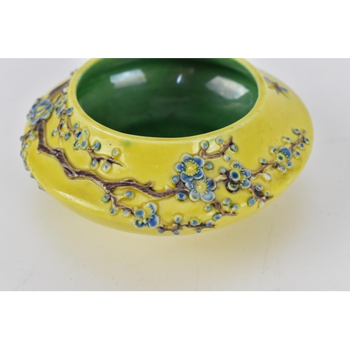 122A - A Chinese yellow ground porcelain bowl, possibly Fahua, with raised prunus branches with blue blooms... 