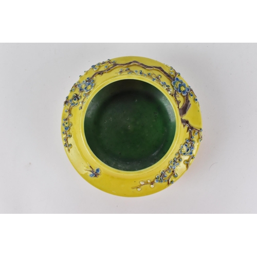 122A - A Chinese yellow ground porcelain bowl, possibly Fahua, with raised prunus branches with blue blooms... 