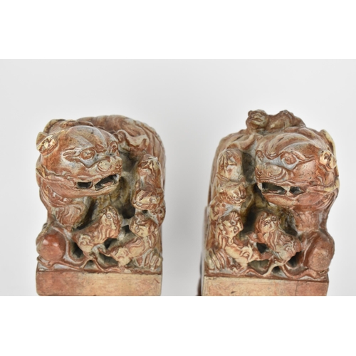 69 - A pair of carved soapstone models of temple guardian Foo dogs, each modelled with a large dog and sm... 