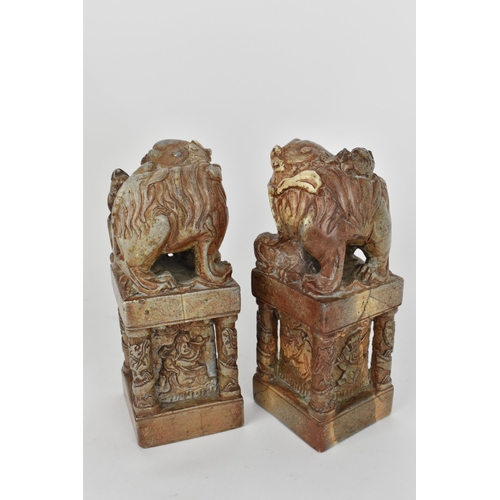 69 - A pair of carved soapstone models of temple guardian Foo dogs, each modelled with a large dog and sm... 